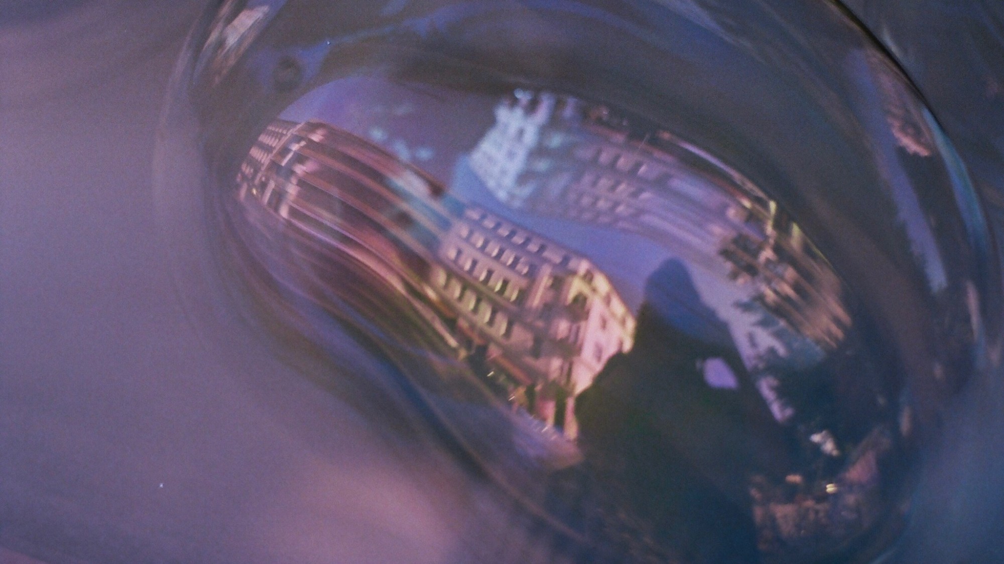 Wassertropfen mit Spiegelbild einer Stadt mit fotografierender Person