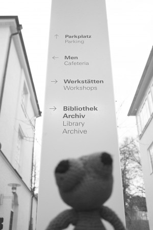 teddy bear looking at sign with directions to different rooms in the inner yard of the university of design in Schwäbisch Gmünd
