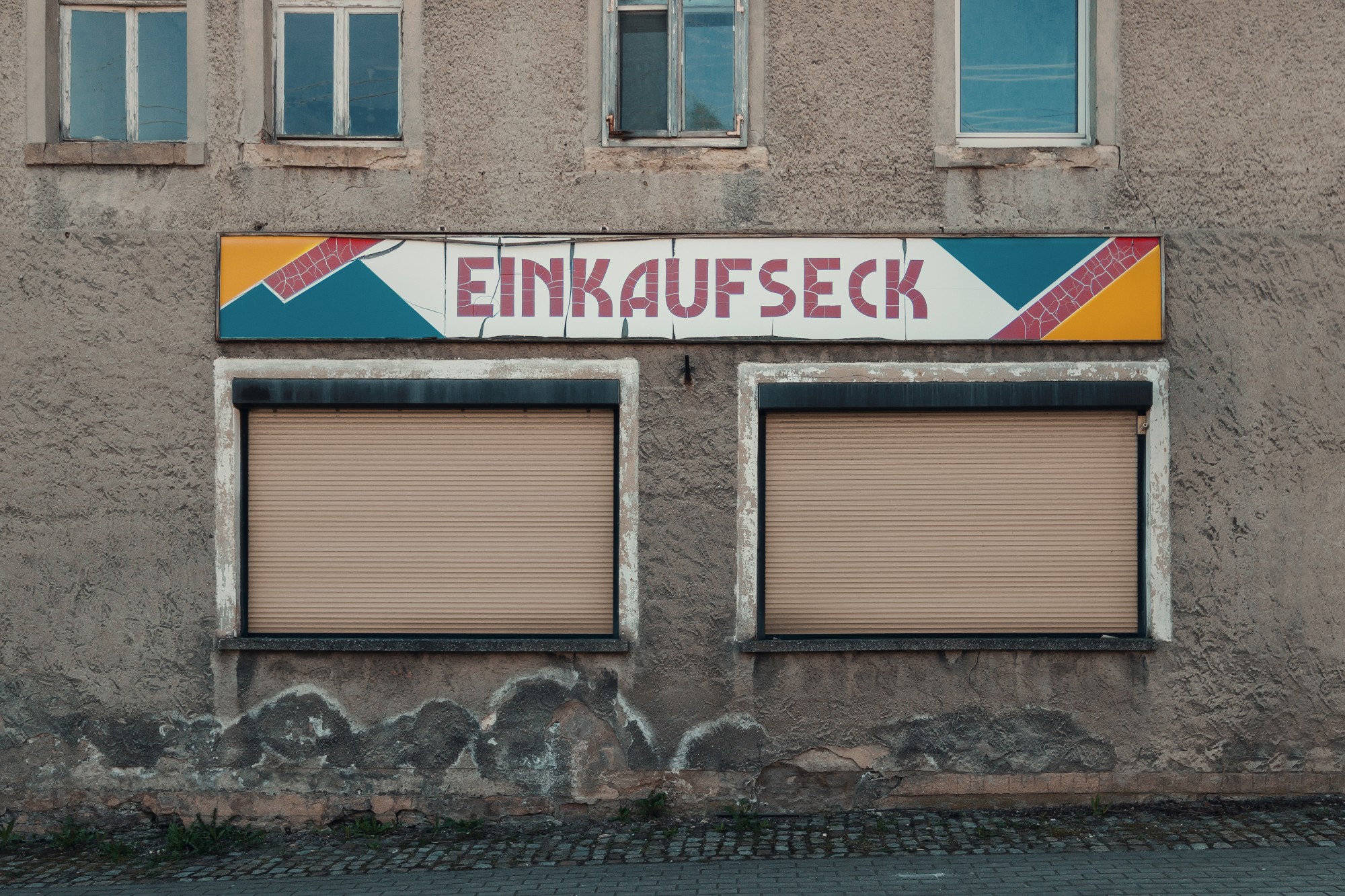 braune Hausfront mit buntem Typografieschild, Einkaufseck