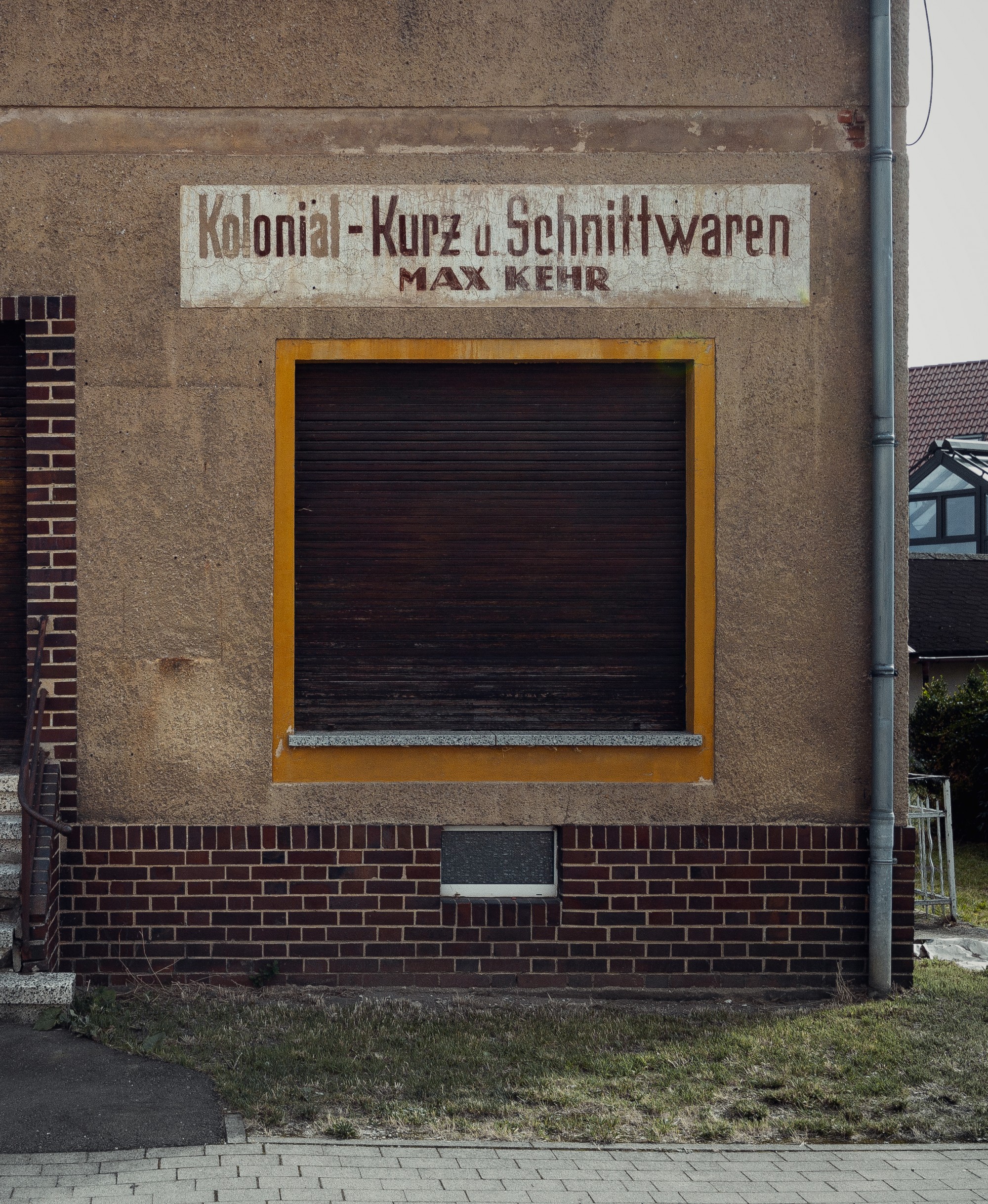 Fassade eines alten Schnittwarenladens mit gelbem Fensterrahmen