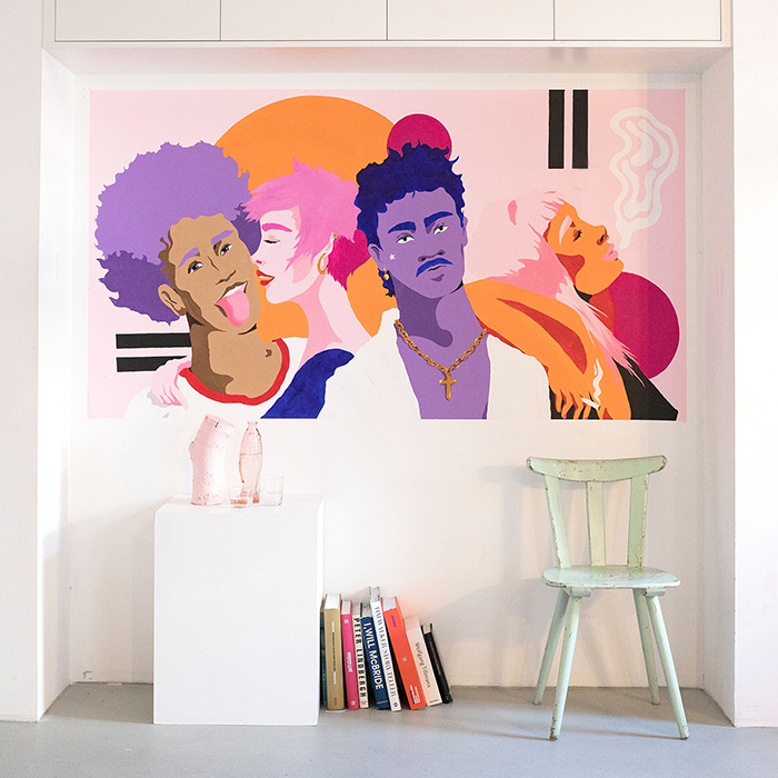Bunte Wandmalerei mit mehreren Personen im illustrativen Stil auf einer weißen Wand, weiße Wohnaccessoires im Vordergrund