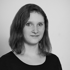 Schwarz-weiß Portrait einer jungen Frau mit schulterlangen dunklen Haaren, die dezent lächelt.